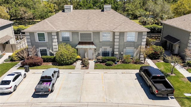14019 Notreville Way, Tampa, FL 33624 - view of front of house featuring uncovered parking, a chimney, a shingled roof, and stucco siding