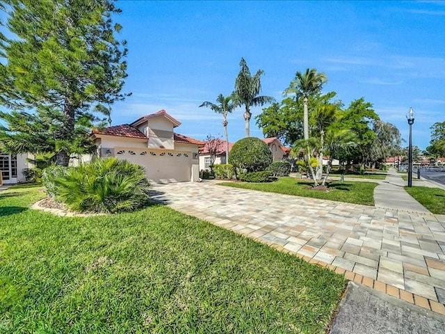 mediterranean / spanish-style home featuring a tile roof, a front yard, stucco siding, and an attached garage