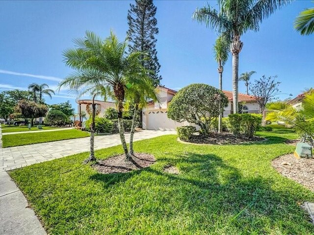 view of front of home featuring driveway, a front yard, a tile roof, stucco siding, and a garage