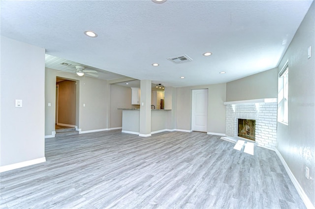 804 Shore Dr W, Oldsmar, FL 34677 - unfurnished living room featuring light wood finished floors, baseboards, visible vents, and a brick fireplace
