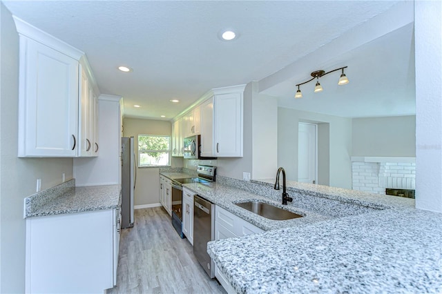 804 Shore Dr W, Oldsmar, FL 34677 - kitchen featuring light stone counters, a sink, light wood finished floors, white cabinetry, and appliances with stainless steel finishes