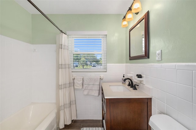 bathroom with wainscoting, vanity, toilet, shower / bath combination with curtain, and tile walls