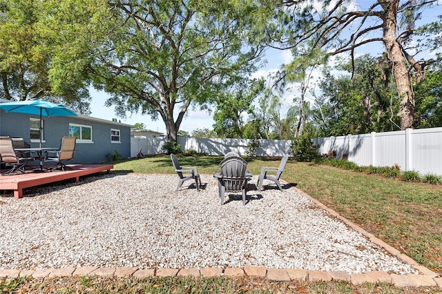 view of yard with a fenced backyard, outdoor dining space, an outdoor fire pit, and a deck