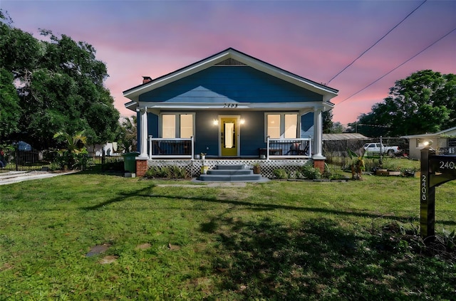 view of front of house featuring a yard, a porch, and fence