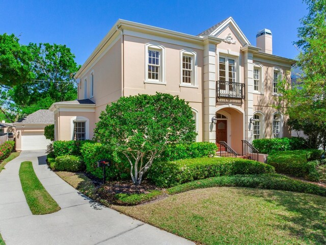 view of front of home featuring a balcony, stucco siding, a chimney, and an attached garage