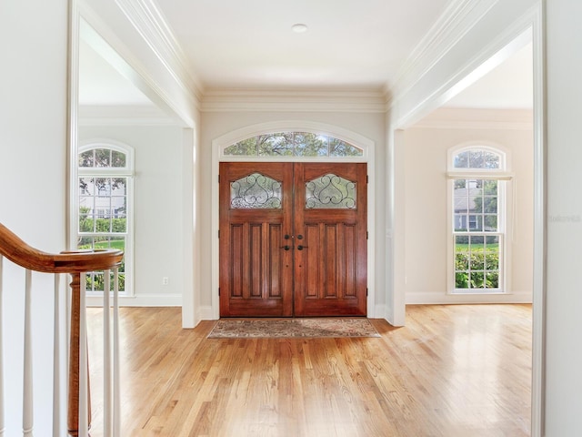 foyer entrance featuring light wood-type flooring, crown molding, and baseboards