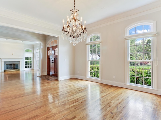 unfurnished living room with a chandelier, ornamental molding, light wood-type flooring, baseboards, and a fireplace