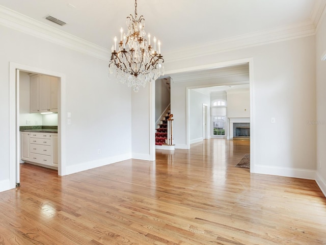 unfurnished dining area featuring stairs, light wood-type flooring, crown molding, a chandelier, and baseboards