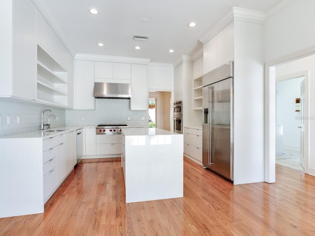 kitchen featuring open shelves, stainless steel appliances, wall chimney exhaust hood, a sink, and modern cabinets