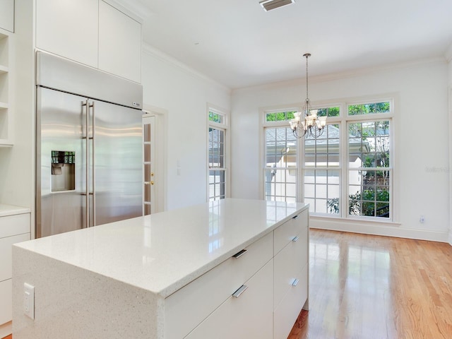 kitchen with stainless steel built in fridge, ornamental molding, light wood-type flooring, a chandelier, and white cabinetry