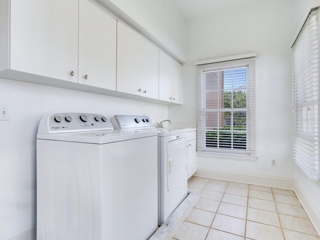 laundry room featuring cabinet space, washer and dryer, light tile patterned floors, and baseboards