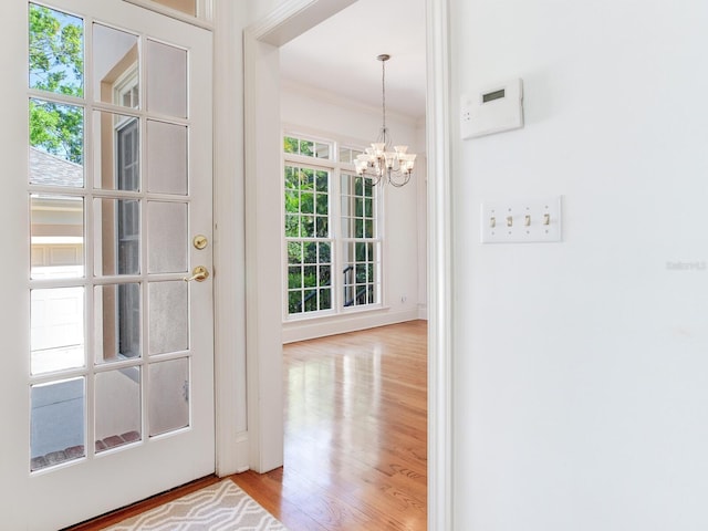 entryway with a chandelier, wood finished floors, and ornamental molding