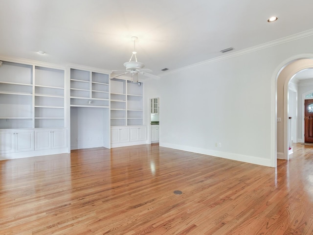 unfurnished living room featuring arched walkways, a ceiling fan, ornamental molding, light wood-style flooring, and baseboards