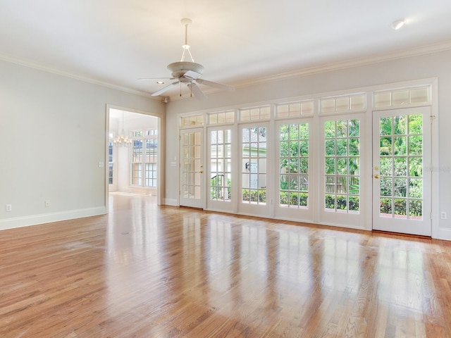 spare room featuring a ceiling fan, a chandelier, baseboards, wood finished floors, and crown molding