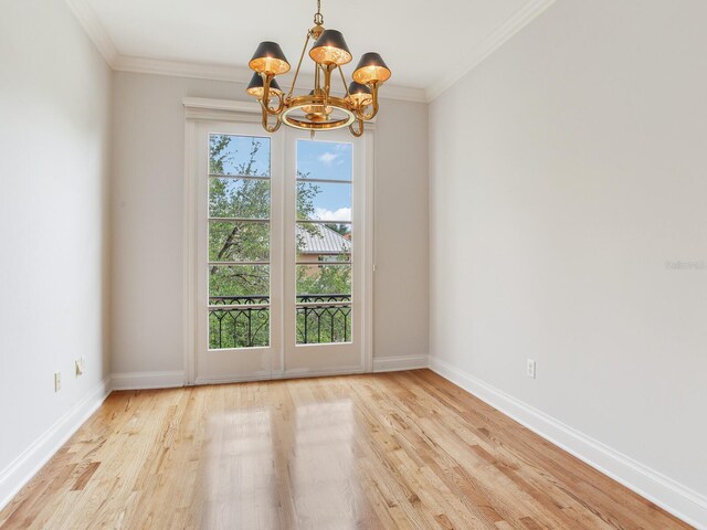 unfurnished room with a chandelier, wood finished floors, baseboards, and ornamental molding