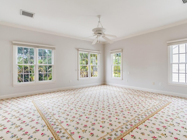 carpeted empty room featuring healthy amount of natural light, ornamental molding, baseboards, and a ceiling fan