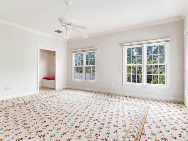carpeted spare room featuring ornamental molding, healthy amount of natural light, baseboards, and a ceiling fan
