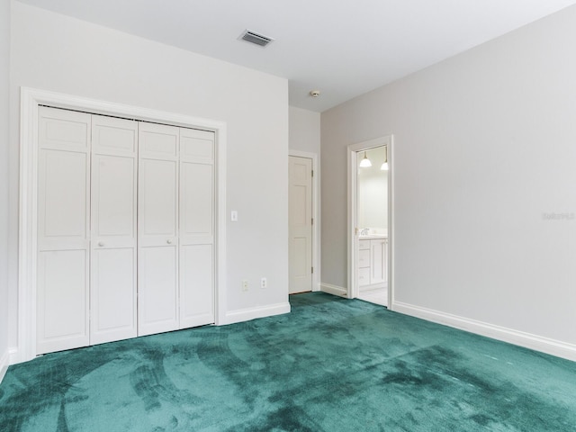 unfurnished bedroom with carpet, baseboards, a closet, and ensuite bathroom