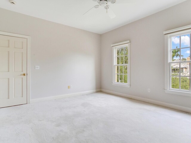 carpeted empty room with ceiling fan, plenty of natural light, and baseboards