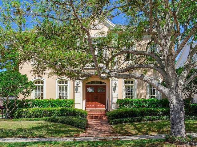 view of property hidden behind natural elements with stucco siding
