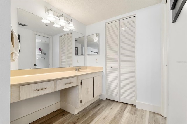 6265 Sun Blvd Unit 1201, Saint Petersburg, FL 33715 - bathroom featuring a closet, wood finished floors, vanity, and a textured ceiling