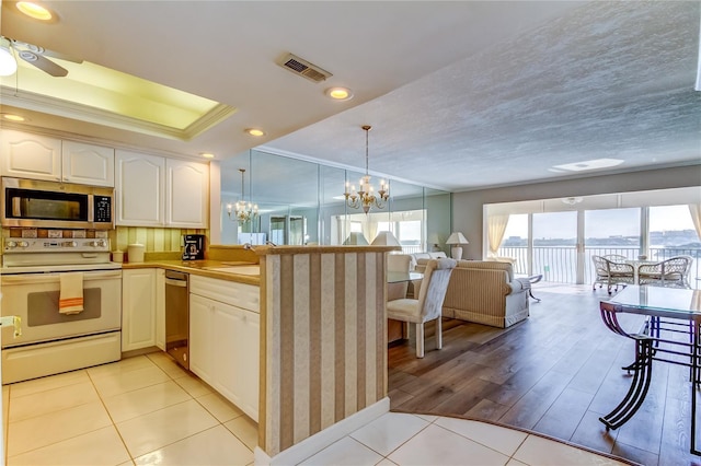 895 S Gulfview Blvd Unit 309, Clearwater Beach, FL 33767 - kitchen featuring stainless steel microwave, white range with electric cooktop, open floor plan, light tile patterned floors, and visible vents
