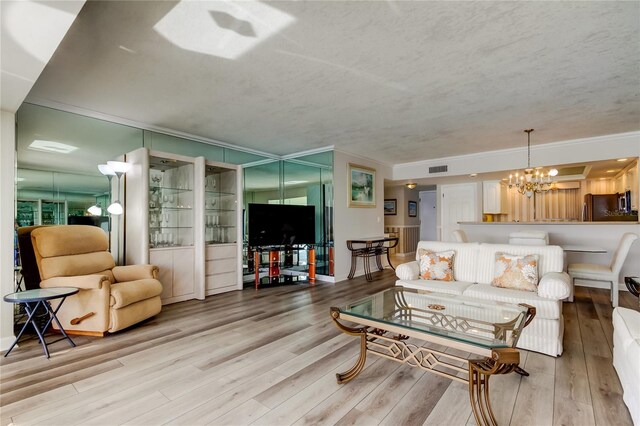 895 S Gulfview Blvd Unit 309, Clearwater Beach, FL 33767 - living room featuring a notable chandelier, wood finished floors, ornamental molding, and a textured ceiling
