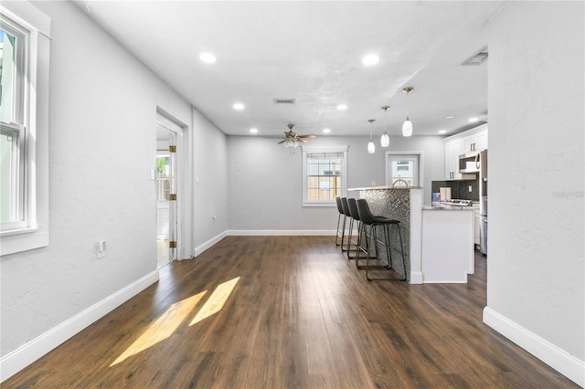kitchen featuring a kitchen breakfast bar, white cabinetry, stainless steel appliances, dark wood-type flooring, and visible vents