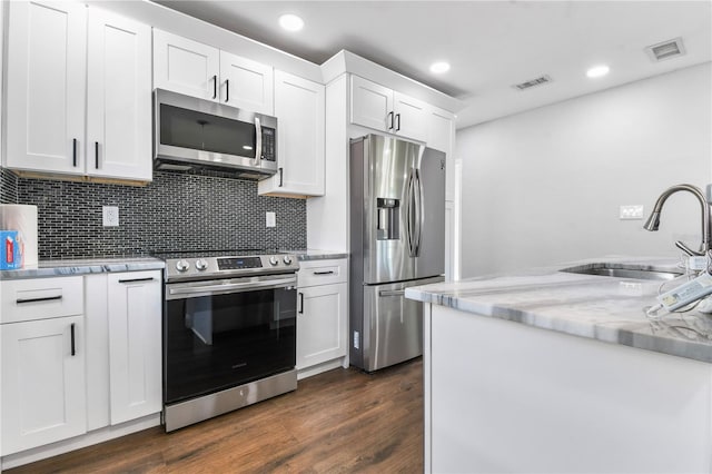 kitchen with a sink, stainless steel appliances, visible vents, white cabinets, and dark wood-type flooring