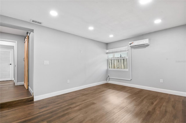 empty room with wood finished floors, a wall mounted AC, recessed lighting, and visible vents