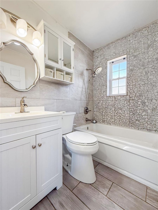 full bath with tile walls, toilet, vanity, shower / washtub combination, and backsplash