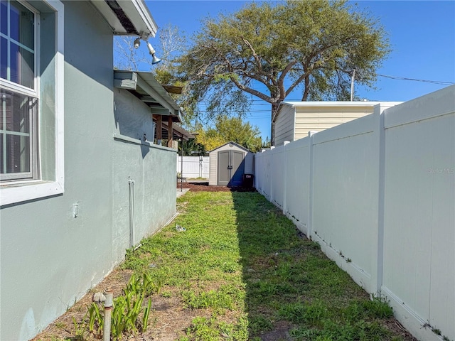 view of yard featuring a storage unit, a fenced backyard, and an outbuilding