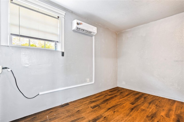 empty room featuring wood finished floors and an AC wall unit