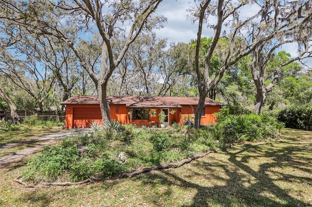 view of front of property featuring a front lawn, fence, driveway, and an attached garage