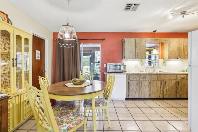 kitchen featuring light tile patterned flooring, light countertops, plenty of natural light, visible vents, and decorative backsplash