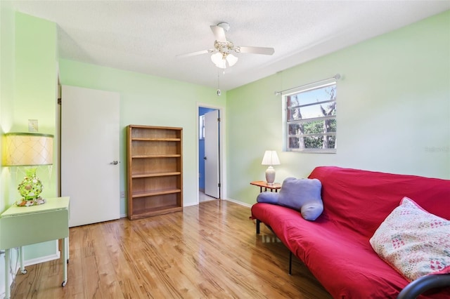 sitting room featuring a textured ceiling, baseboards, ceiling fan, and wood finished floors