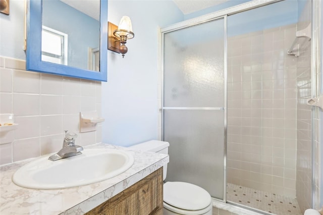 bathroom featuring vanity, toilet, a shower stall, and tasteful backsplash