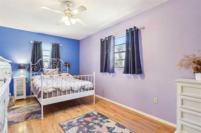 bedroom featuring a ceiling fan, a textured ceiling, baseboards, and wood finished floors