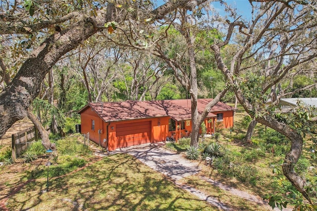 view of front facade with a wooded view, a front yard, driveway, and a garage