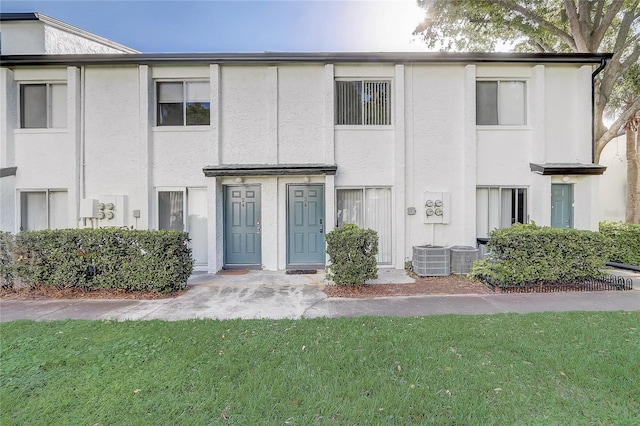 multi unit property featuring stucco siding, a front lawn, and central AC