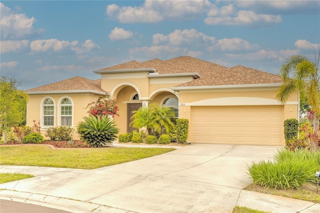 mediterranean / spanish home with roof with shingles, a front lawn, driveway, an attached garage, and stucco siding