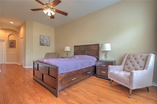 bedroom featuring recessed lighting, a ceiling fan, arched walkways, light wood-type flooring, and baseboards