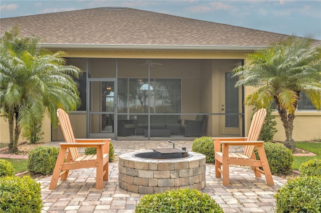 view of patio featuring ceiling fan, a sunroom, and an outdoor fire pit