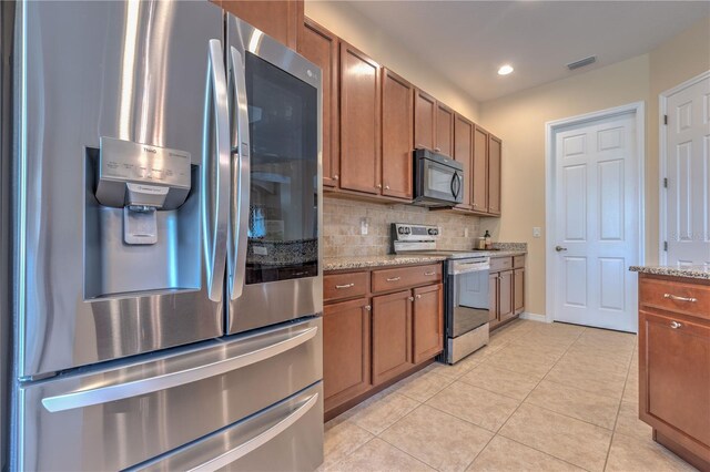 2218 132nd Pl E, Parrish, FL 34219 - kitchen featuring brown cabinetry, stainless steel appliances, decorative backsplash, and light tile patterned floors