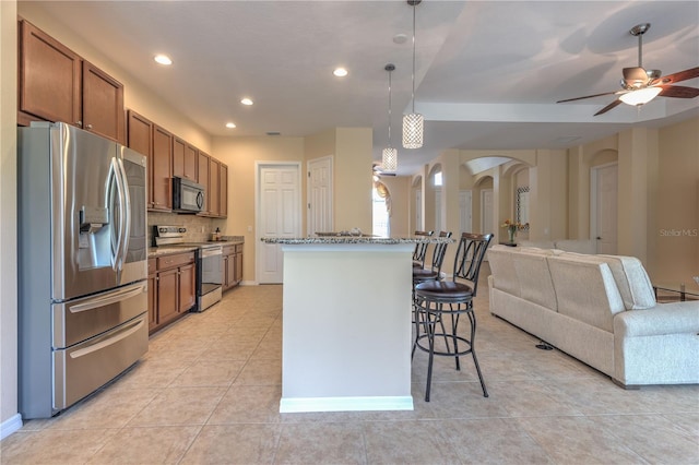 2218 132nd Pl E, Parrish, FL 34219 - kitchen with stainless steel appliances, arched walkways, a kitchen breakfast bar, open floor plan, and brown cabinets