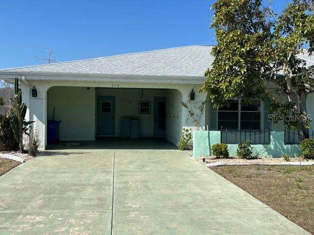 view of front of property featuring stucco siding, concrete driveway, a carport, and a shingled roof