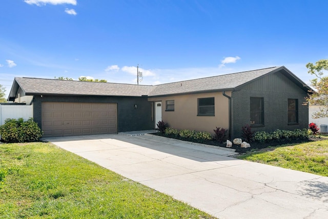ranch-style house with a front lawn, concrete driveway, a shingled roof, and a garage