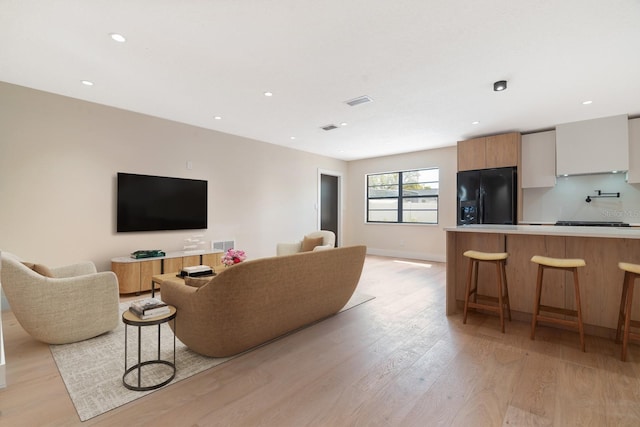 living room featuring light wood finished floors, recessed lighting, and baseboards