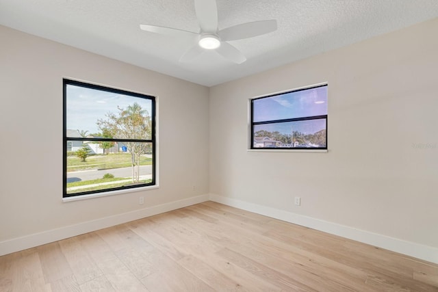 unfurnished room featuring baseboards, light wood-style flooring, a ceiling fan, and a textured ceiling