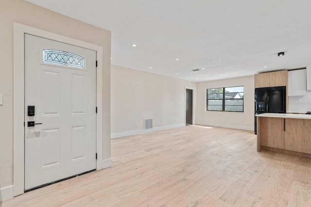 foyer entrance with light wood-style floors, baseboards, and recessed lighting